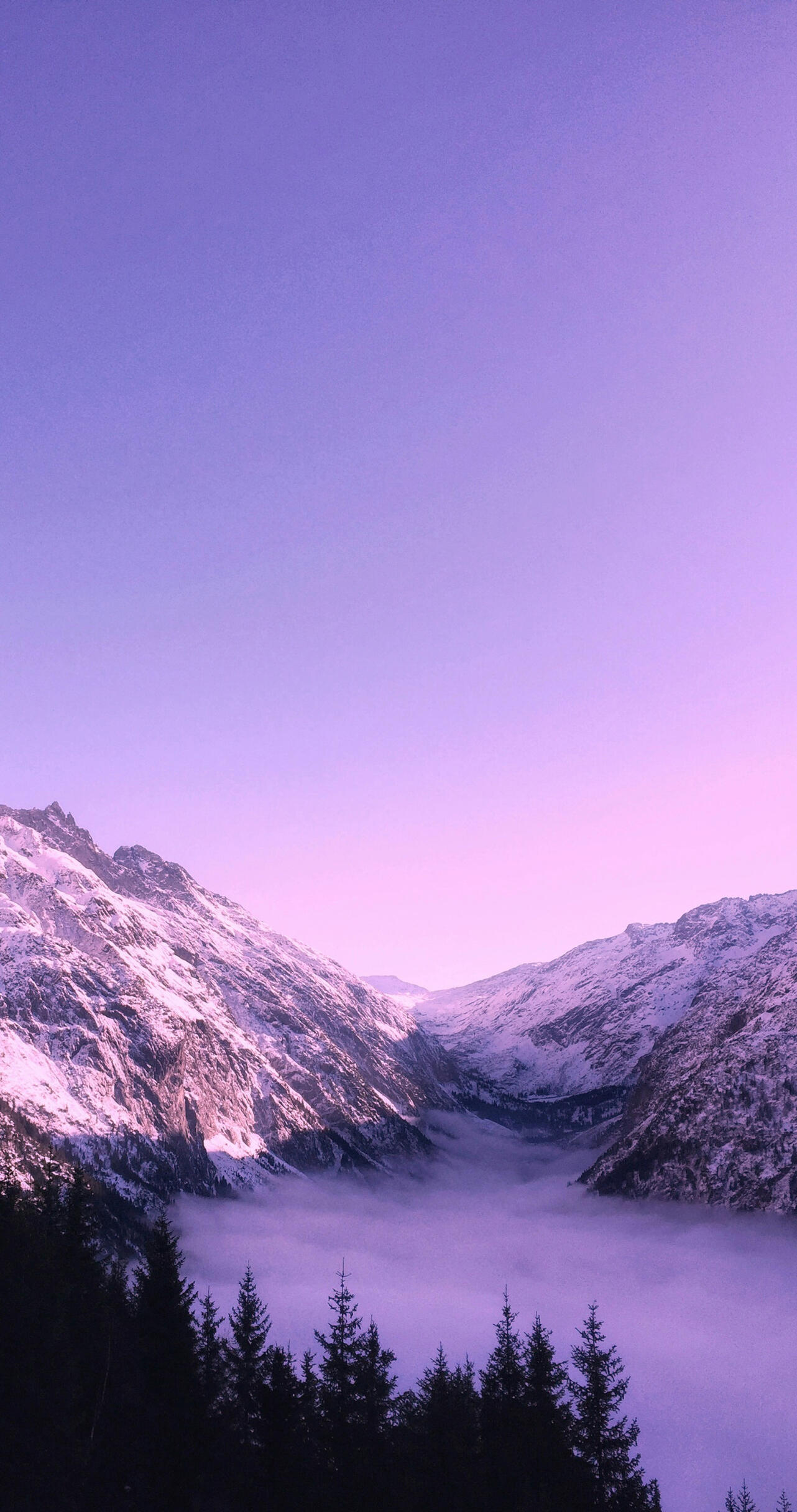 The image depicts a purple-blue sky with mountains at the bottom. Fog fills the spot between the mountains.